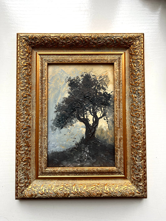 Framed painting of a tree with intricate gold frame on a white wall