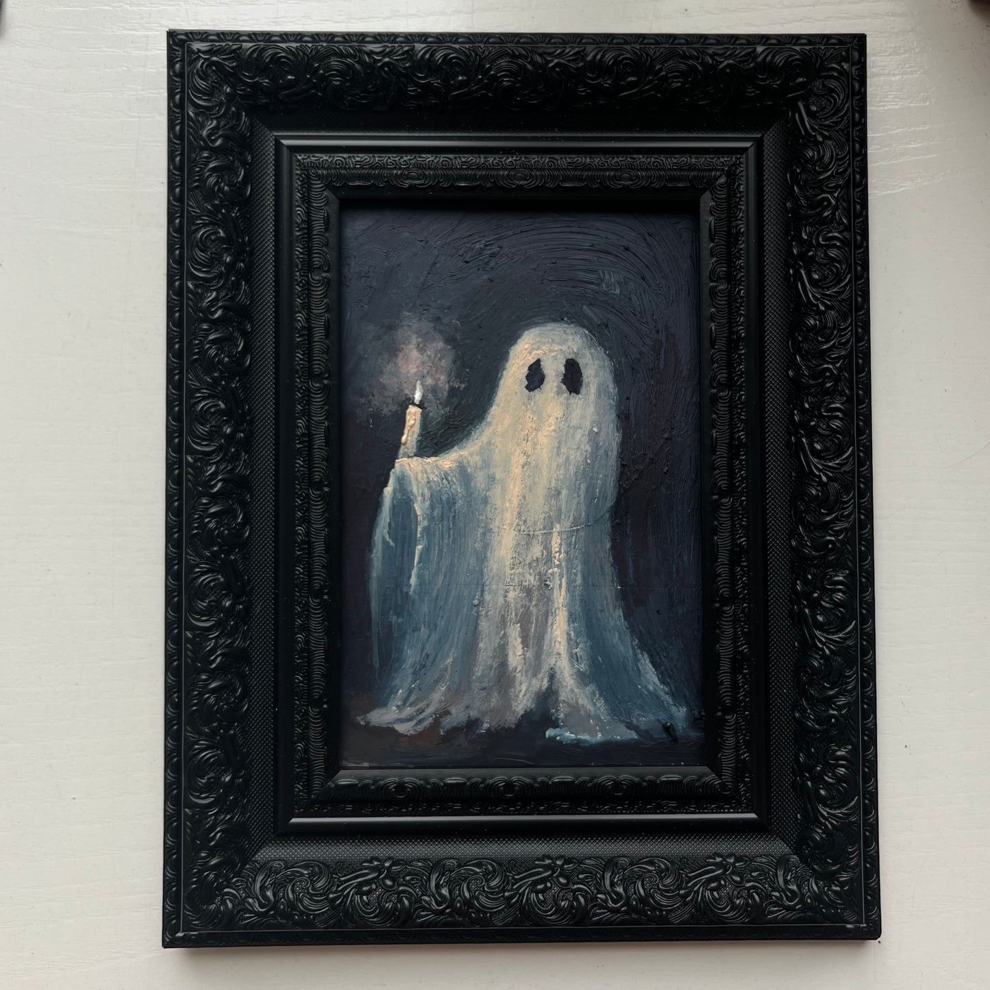 Framed artwork of a ghost holding a candle against a dark background
