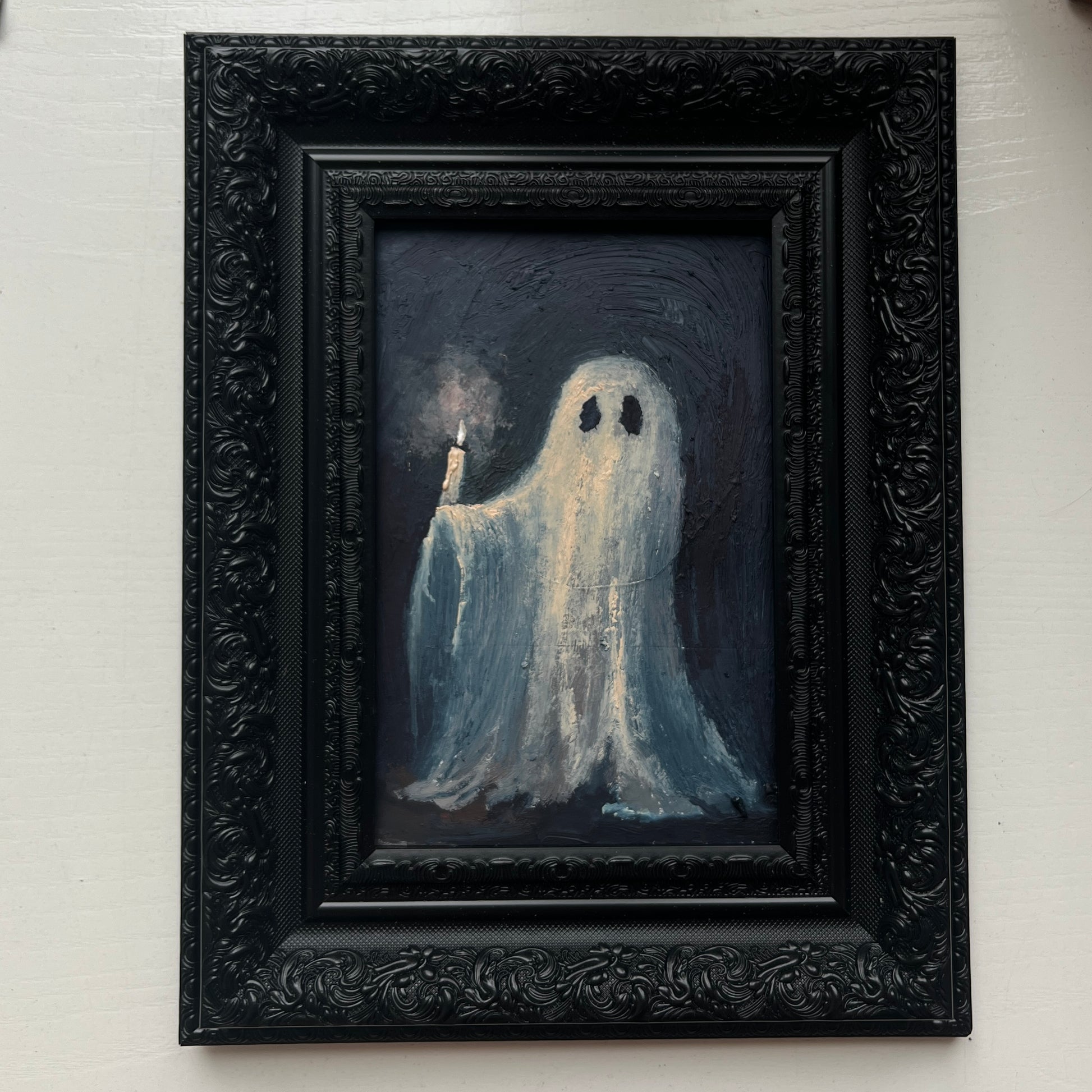 Framed artwork of a ghost holding a candle against a dark background